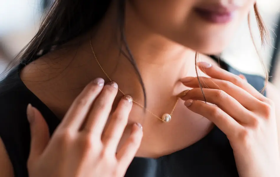 Young woman trying on neck an elegant pearl jewelry.Get dressed for the celebration