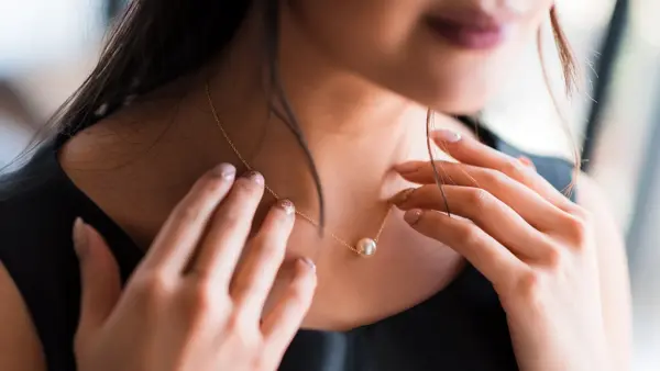 Young woman trying on neck an elegant pearl jewelry.Get dressed for the celebration