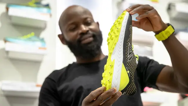 Bilde av mann som viser løpesko med pigger