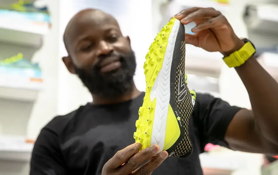 Bilde av mann som viser løpesko med pigger