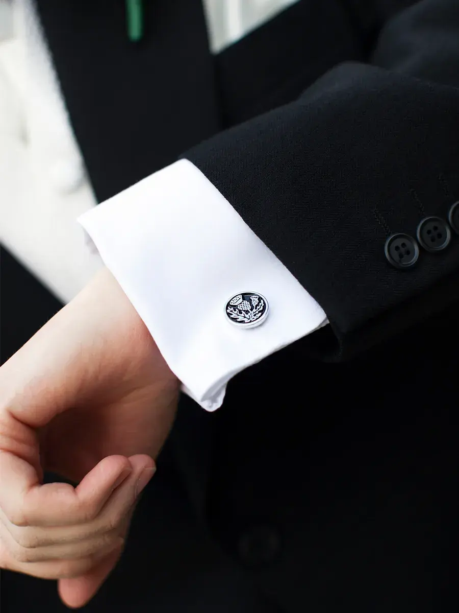 utsnitt av skjorteerme og mansjettknapp til mann som har på dress