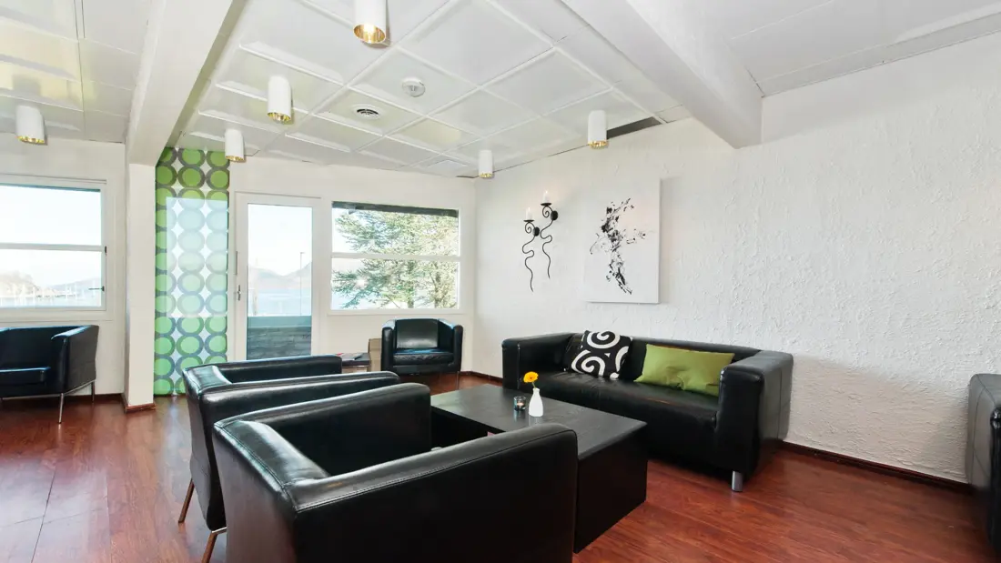 Lobbyområdet med sorte sittemøbler og grønne detaljer hos Thon Hotel Sandnes