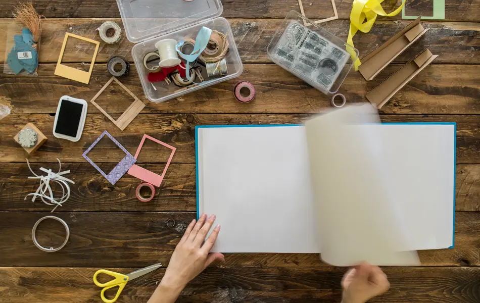Top view of woman's hands preparing a scrapbook