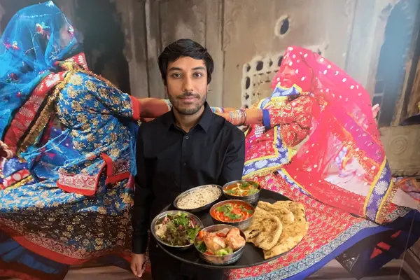 Servitør med stort fat med indiske retter