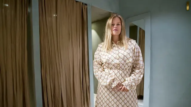 Jente med blondt hår, har på seg en mønstrete kjole 