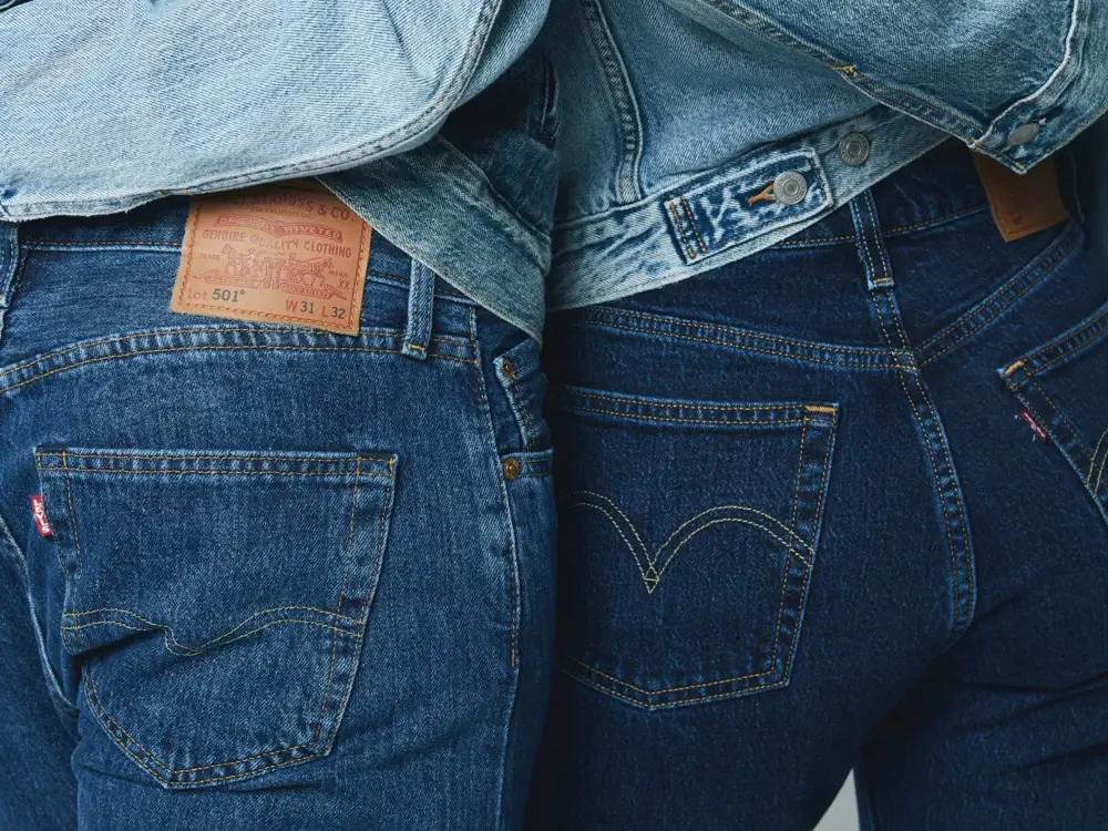 Nærbilde av bakdelen til to mennesker, hvor begge har på mørke jeans og holder rundt livet til hverandre