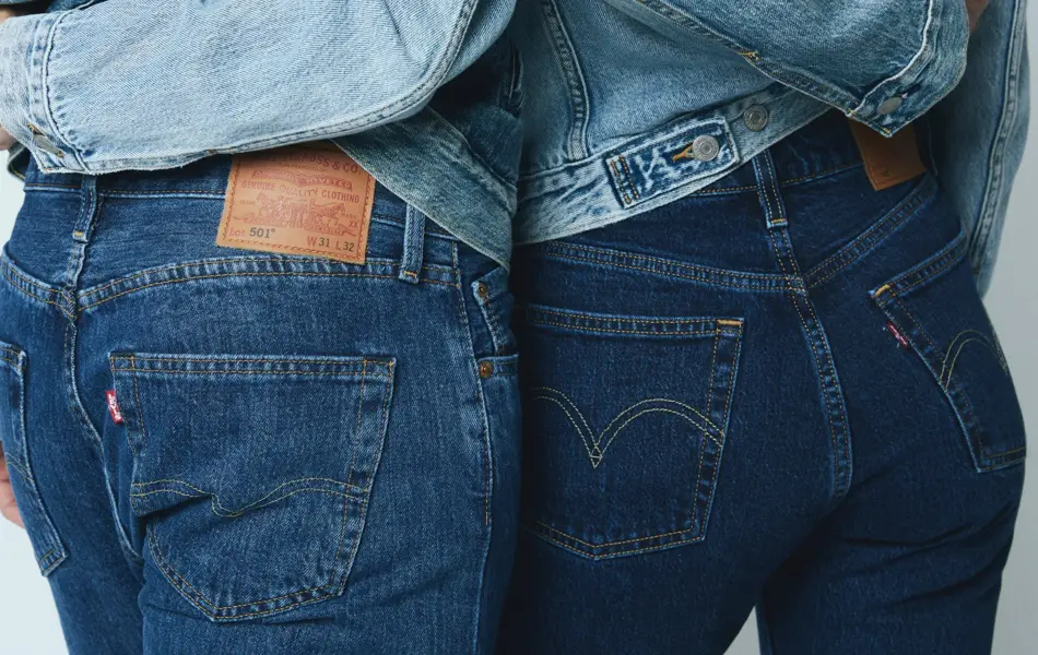 Nærbilde av bakdelen til to mennesker, hvor begge har på mørke jeans og holder rundt livet til hverandre