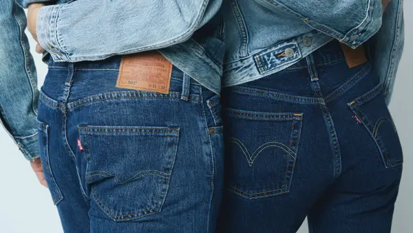 Nærbilde av bakdelen til to mennesker, hvor begge har på mørke jeans og holder rundt livet til hverandre