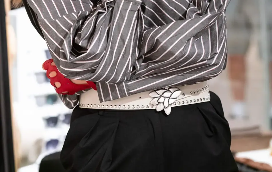 Ung kvinne med røde skinnhansker og stripete bluse står med hodet vendt til siden