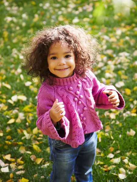 smilende jente som har på seg rosa genser og jeans