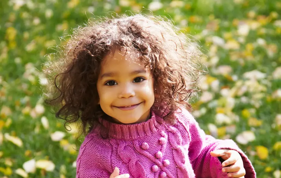 smilende jente som har på seg rosa genser og jeans