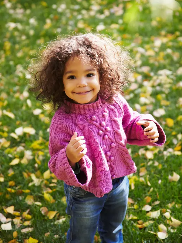 smilende jente som har på seg rosa genser og jeans