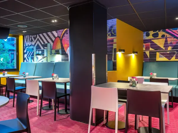 Frokostsalen hos Thon Hotel Trondheim. Veggene er malt med grafittiuttrykk, turkise sofaer, hvite og sorte stoler, spisebord, rosa gulvteppe.