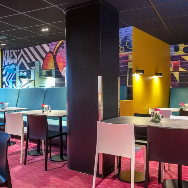 Frokostsalen hos Thon Hotel Trondheim. Veggene er malt med grafittiuttrykk, turkise sofaer, hvite og sorte stoler, spisebord, rosa gulvteppe.