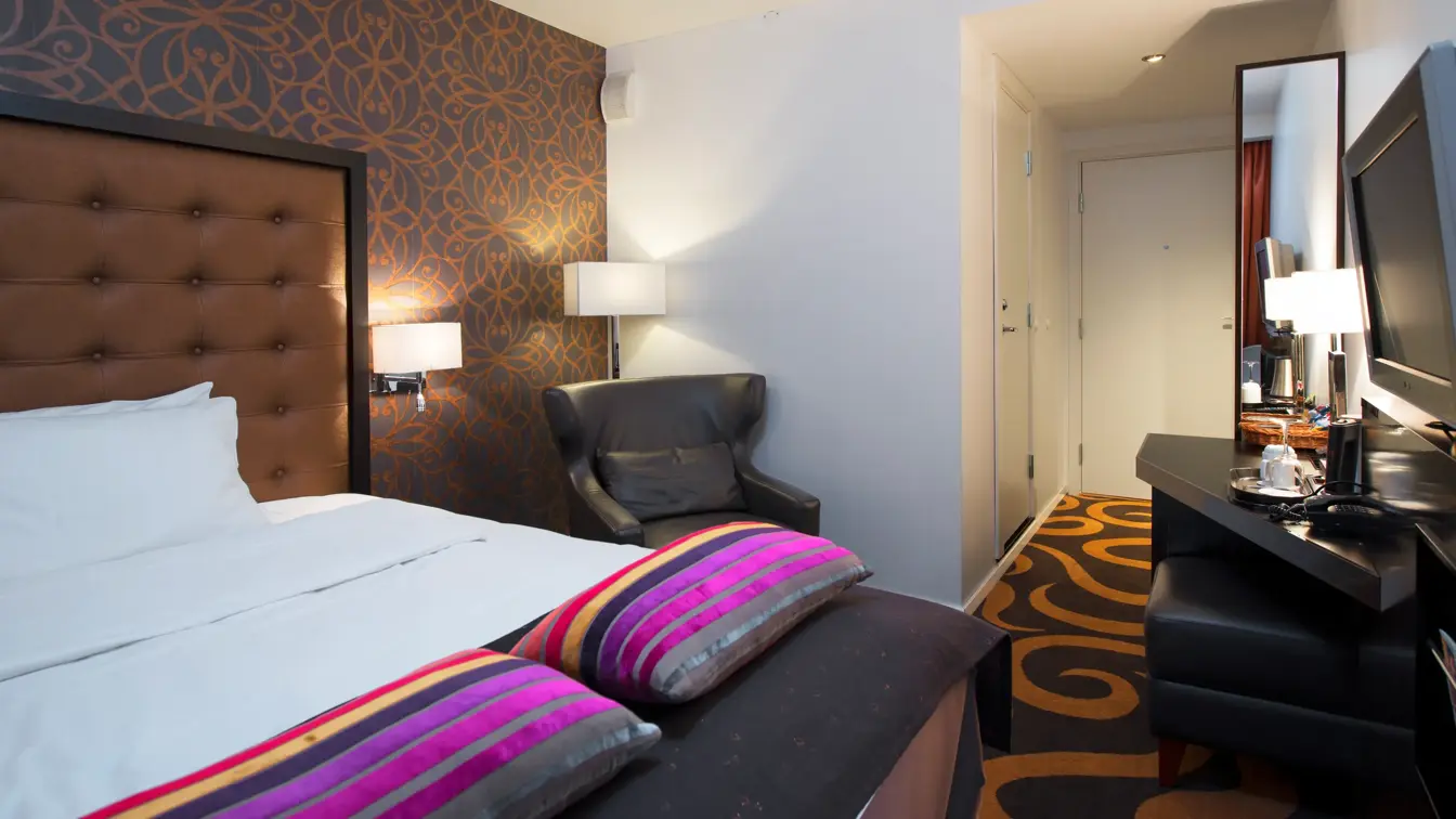 Dobbeltseng, lenestol og tv på Thon Hotel Linne i Oslo