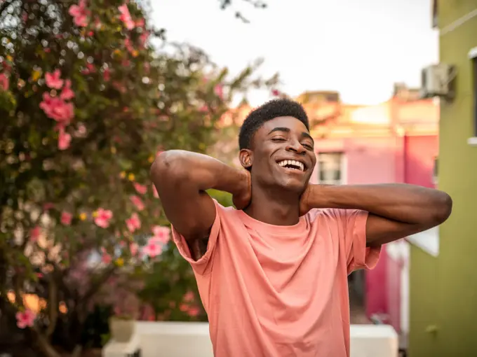 Mann ser mot kamera og smiler med blomster i bakgrunnen 