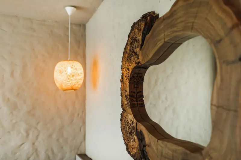 Speil med naturlig ramme av mørkt tre hengende på bad med hvite murvegger 