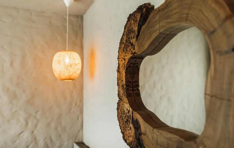 Speil med naturlig ramme av mørkt tre hengende på bad med hvite murvegger 