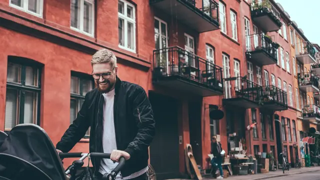 Halvnært bilde av en far som går tur med barnet sitt i vogn