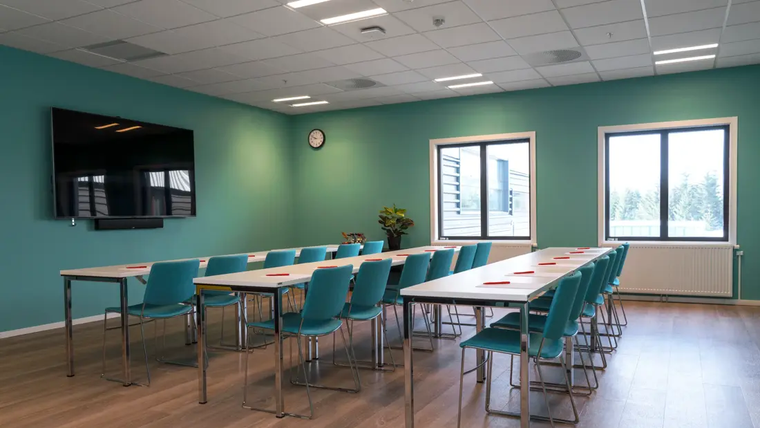 Møterom Terminalenmed TV-skjerm, klasseromsoppett og turkise stoler og vegger på Thon Hotel Gardermoen