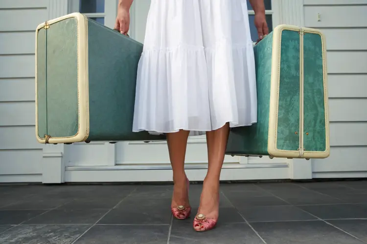 Dame som holder to grønne kofferter