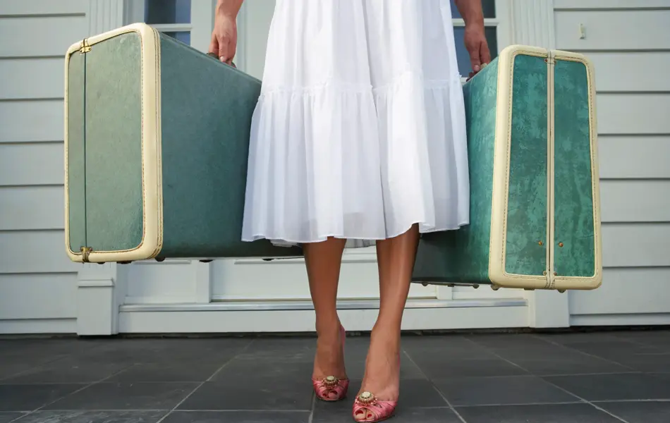 Dame som holder to grønne kofferter