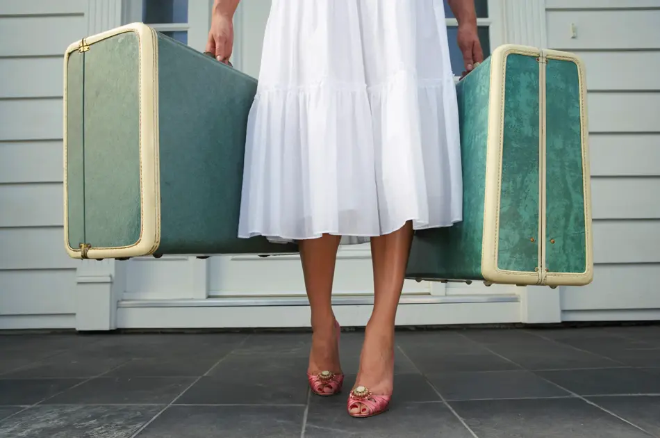 Dame som holder to grønne kofferter