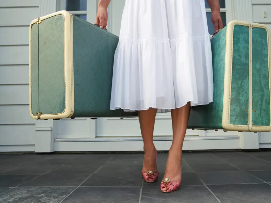 Dame som holder to grønne kofferter