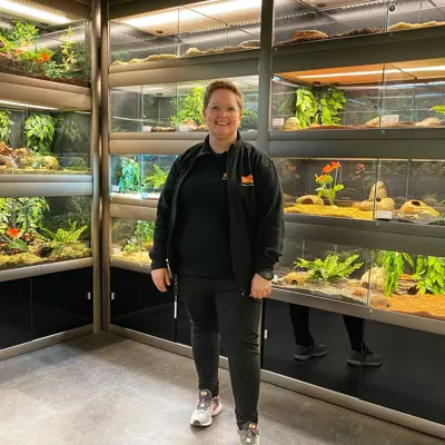 Dame står foran bur som inneholder reptiler