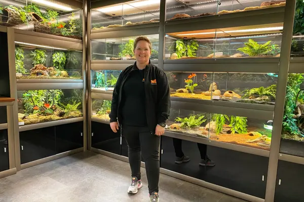 Dame står foran bur som inneholder reptiler