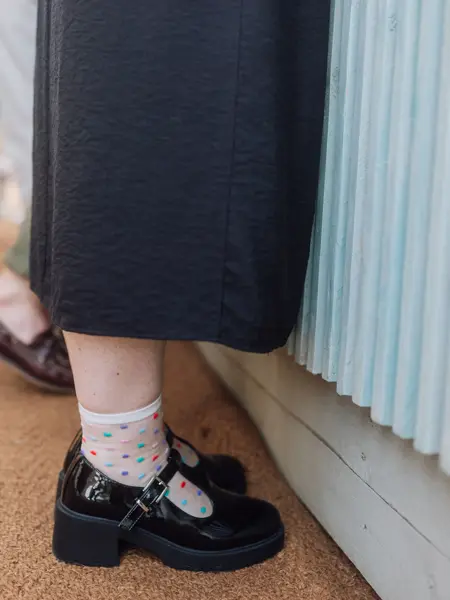 Nærbilde av sorte Mary Janes med prikkete sokker 