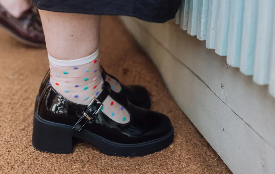 Nærbilde av sorte Mary Janes med prikkete sokker 