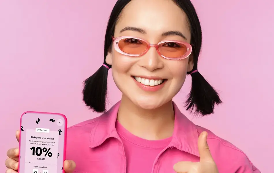 Dame med rosa solbriller og rosa jakke holder mobil med kupongkode