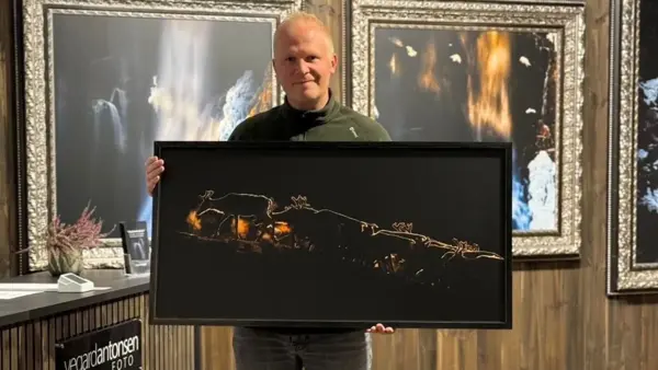 Vegard Antonsen står og poserer med et av bildene sine