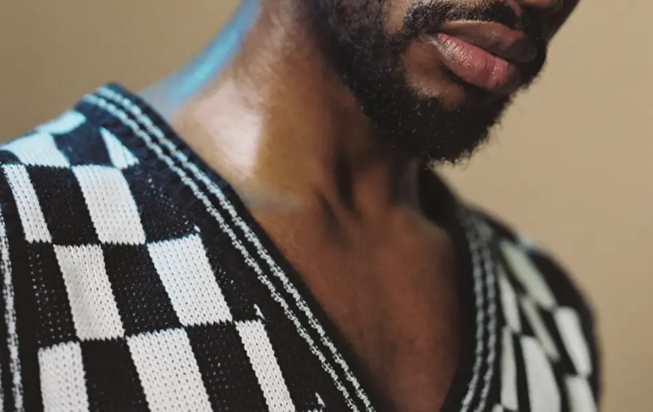 Nærbilde av mann iført svart- og hvitrutete v-halsgenser