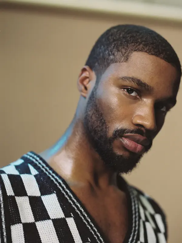 Nærbilde av mann iført svart- og hvitrutete v-halsgenser