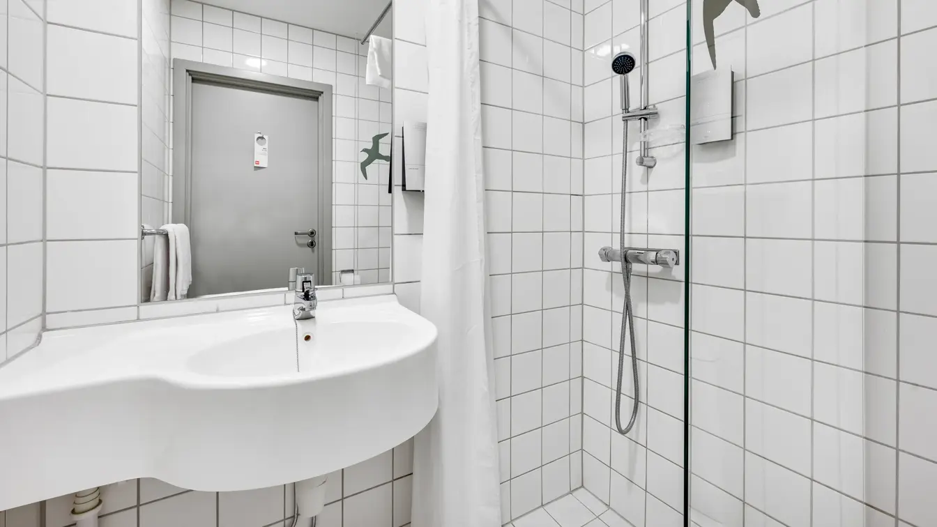 Hvite veggfliser, hvite gulvfliser, dusj, vask, speil