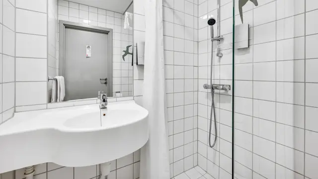 Hvite veggfliser, hvite gulvfliser, dusj, vask, speil