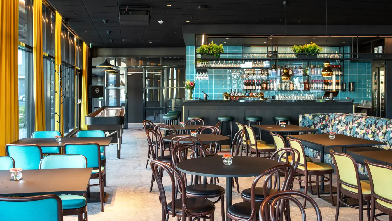 Vindu fra gulv til tak, spisebord, spisesofa, runde bord, blå stoler, gule stoler, bar