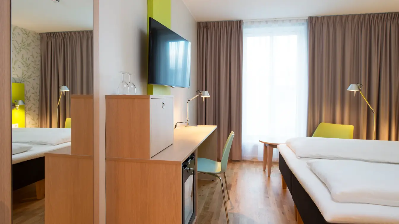 Dobbeltseng med blomstertapet, tv og skrivepult på double room på Thon Hotel Sandven i Nordheimsund