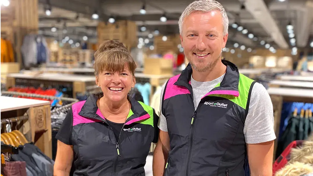 Ansatt dame og mann som smiler i butikken