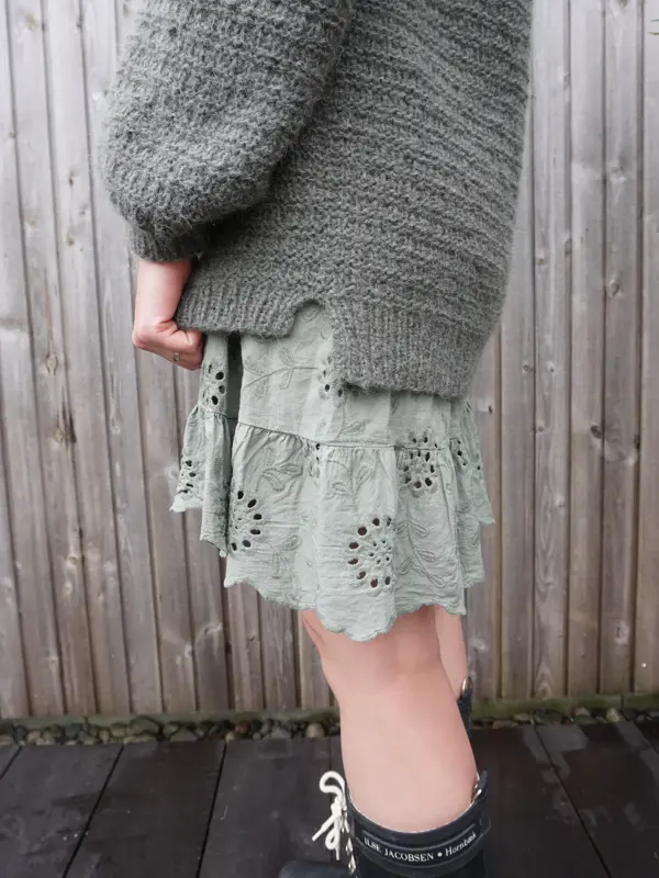 Dame i grønt skjørt og strikket genser