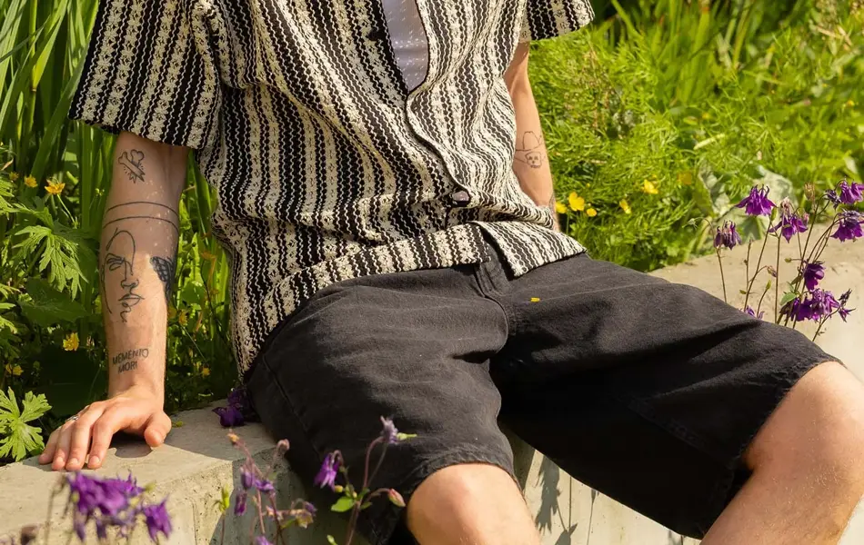 Mann som sitter på en lav vegg og soler seg