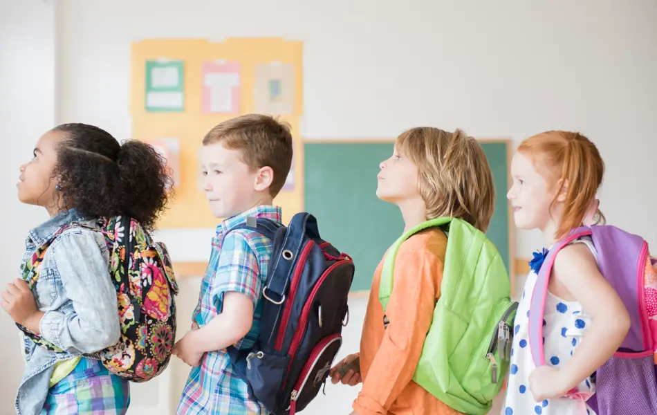 Students wearing backpacks in classroom