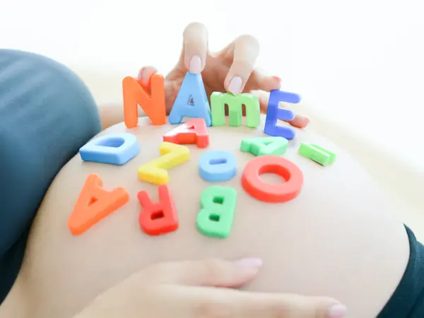 Young expectant mother with letter blocks spelling name on her pregnant belly