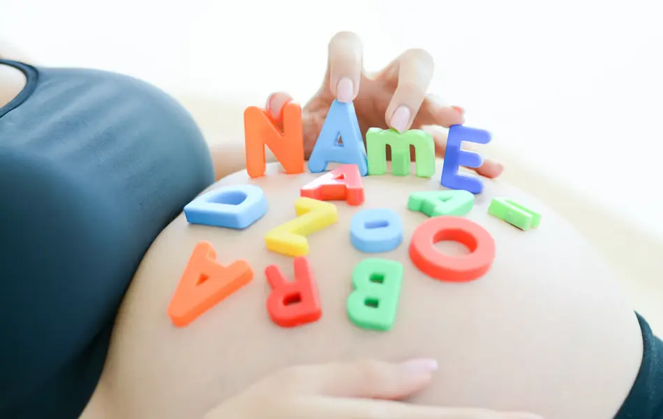 Young expectant mother with letter blocks spelling name on her pregnant belly