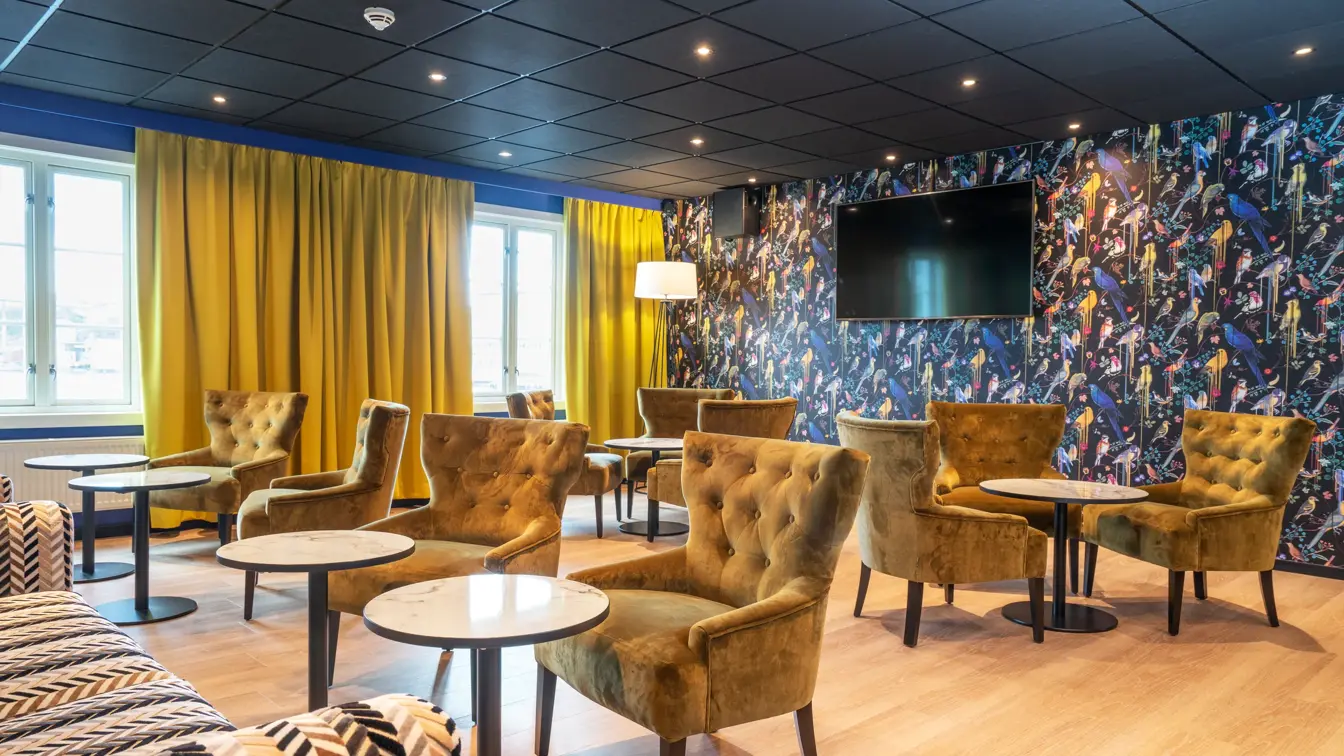 Lounge med sittegrupper, fargerik fugltapet og gule gardiner på Thon Hotel Kristiansund
