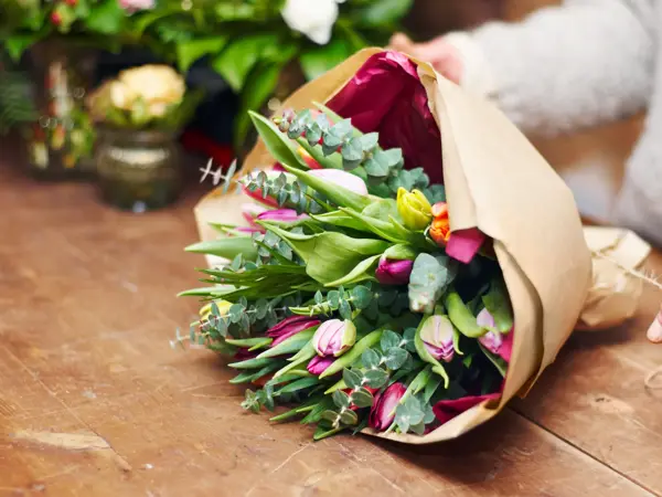 Cropped shot of a pretty floral bouquet being completed on a wooden counter top