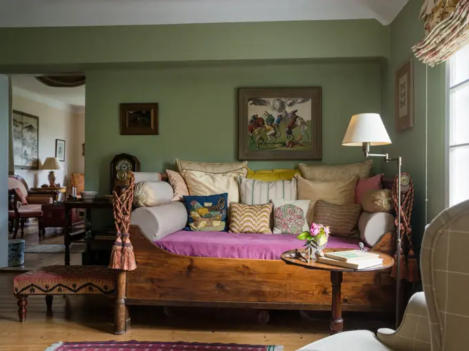 Assorted cushions on antique daybed in in sitting room with kelim upholstered ottoman