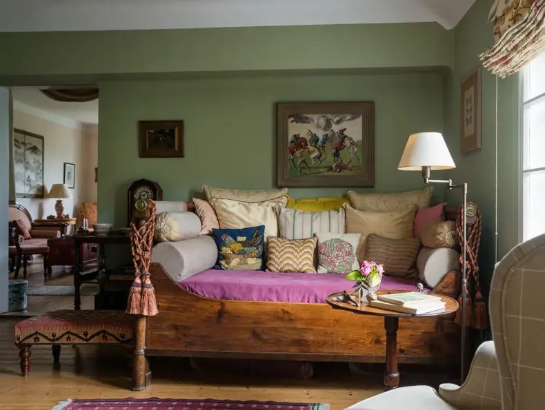 Assorted cushions on antique daybed in in sitting room with kelim upholstered ottoman